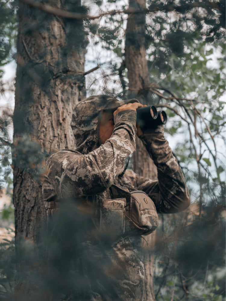 Person in camouflage gear using binoculars 